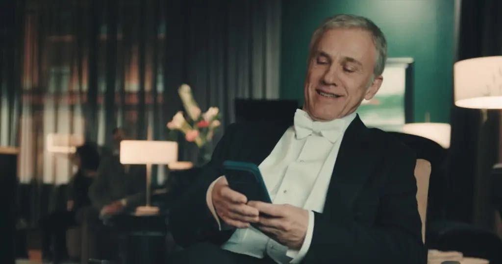 Bitpanda TVC mit Christoph Waltz: Mann im Smoking schaut auf ein Smartphone